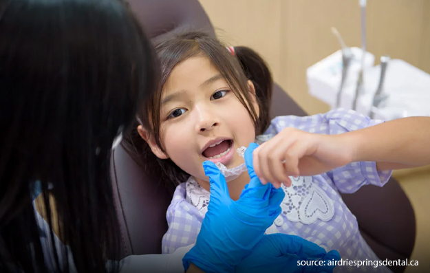 An orthodontist putting on an invisalign to a kid-Invisalign For Kids